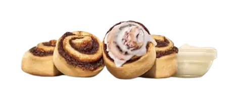 Four mini cinnamon rolls grouped together next to a small container of white icing dip.