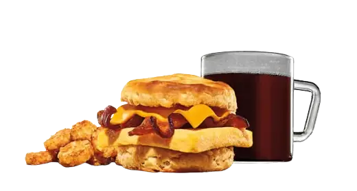 A breakfast biscuit sandwich with bacon, egg, and cheese, served with hashbrowns and a glass mug of black coffee.