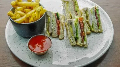 Three-layered club sandwich triangles served on a white speckled plate