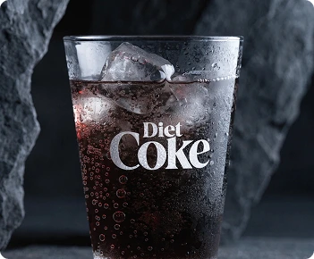 Diet Coke logo on a chilled glass with a dark grey stone background.