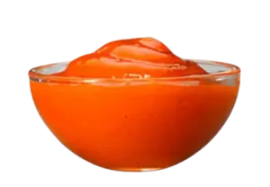 A small clear glass bowl filled with orange sweet and sour dipping sauce.