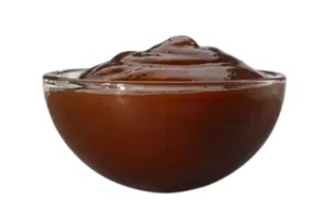 A small clear glass bowl filled with dark brown barbecue dipping sauce.