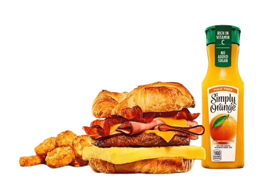 Fully loaded breakfast croissant meal with juice.