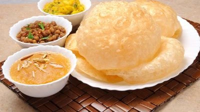 Traditional breakfast with fluffy puris, sweet halwa, and chickpea curry.