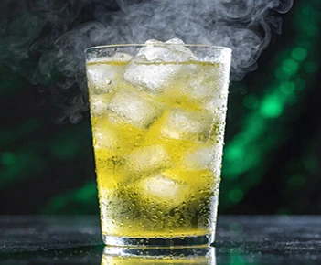 Bright yellow drink with ice cubes and steam or mist rising from the glass.