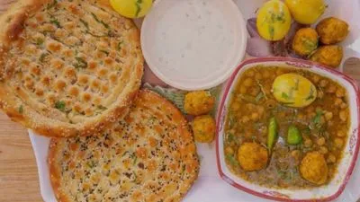 A traditional breakfast platter featuring two sesame-topped naans