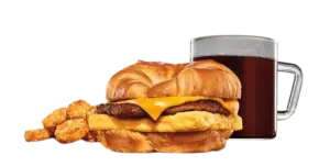 Sausage croissant sandwich with coffee and sides.